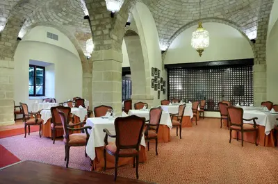 a dining room with tables and chairs and a chandelier at Crisol Monasterio de San Miguel in El Puerto de Santa María