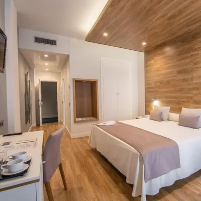 a bedroom with a large white bed and a desk at Hotel Monte Puertatierra in Cádiz