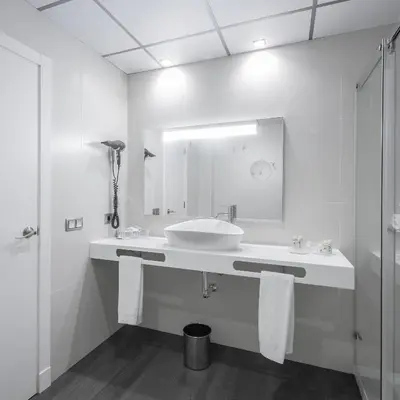 a white bathroom with a sink and a mirror at Hotel Monte Puertatierra in Cádiz