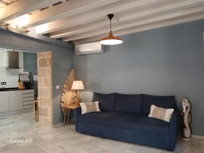 a living room with a blue couch and a kitchen at Apartamento 