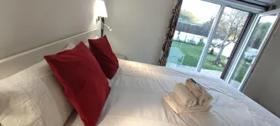 a white bed with red pillows and a pair of shoes at casa de vicky in El Puerto de Santa María