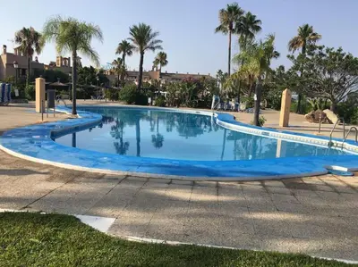 a large blue swimming pool with palm trees in the background at Moderno apartamento en Bahia Sur in San Fernando