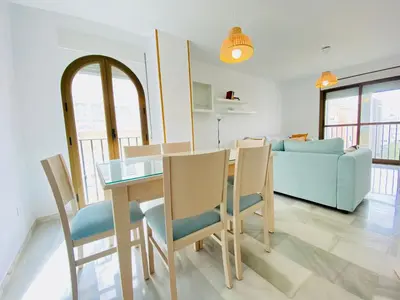 a dining room and living room with a table and chairs at Botánico Playa y Ascensor Grupo AC Gestion in Cádiz