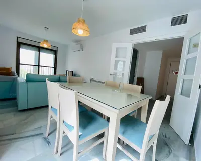 a dining table and chairs in a living room at Botánico Playa y Ascensor Grupo AC Gestion in Cádiz