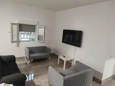 a living room with two chairs and a tv at Precioso bajo muy grande a 200 metros de playa in Chipiona