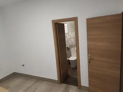 a bathroom with a toilet and a wooden door at Precioso bajo muy grande a 200 metros de playa in Chipiona