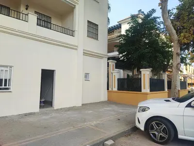 a white car parked in front of a white building at Precioso bajo muy grande a 200 metros de playa in Chipiona