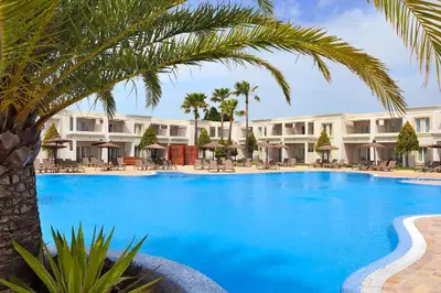a large swimming pool with a palm tree in front of a hotel at Vincci Resort Costa Golf in Chiclana de la Frontera