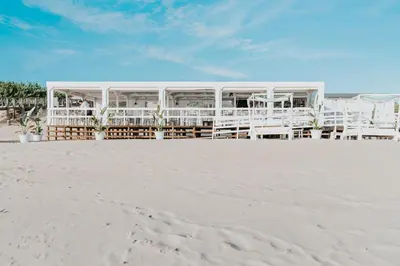 a building on the beach with white chairs at Vincci Resort Costa Golf in Chiclana de la Frontera