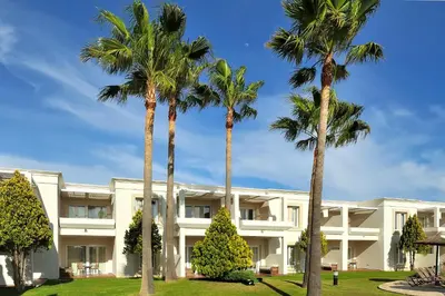 a building with palm trees in front of it at Vincci Resort Costa Golf in Chiclana de la Frontera