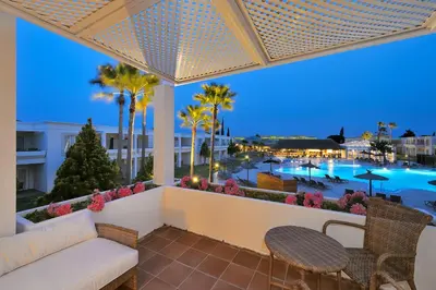 a balcony with a couch and chairs and a view of a pool at Vincci Resort Costa Golf in Chiclana de la Frontera