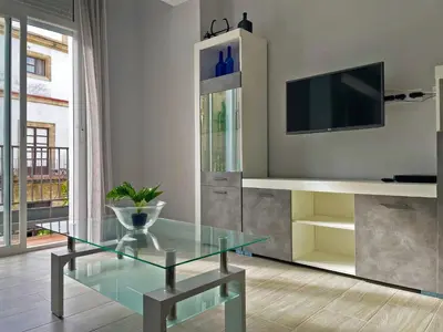 a living room with a glass table and a tv at Apartamento La Catedral - Ole Solutions in Jerez de la Frontera