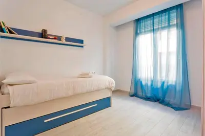 a bedroom with a bed and a window with blue curtains at La Torre de la Catedral - Ole Solutions in Jerez de la Frontera