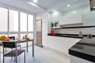 a kitchen with white cabinets and a table with a chair at La Torre de la Catedral - Ole Solutions in Jerez de la Frontera