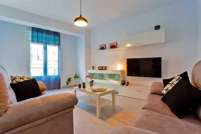 a living room with a couch and a tv and a table at La Torre de la Catedral - Ole Solutions in Jerez de la Frontera