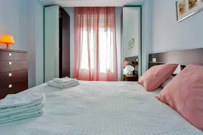 a bedroom with a large white bed with pink pillows at La Torre de la Catedral - Ole Solutions in Jerez de la Frontera