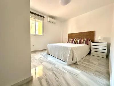 a white bedroom with a bed and a window at Apartamento Plaza Toros in El Puerto de Santa María