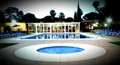 a large swimming pool with chairs and a building at Hotel Dunas Puerto in El Puerto de Santa María