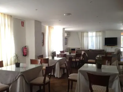 a restaurant with tables and chairs and a television at Hotel Dunas Puerto in El Puerto de Santa María