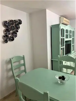 a dining room with a green table and chairs at Piso Calzada de la Infanta Tres Carabelas Sanlúcar de Barrameda in Sanlúcar de Barrameda