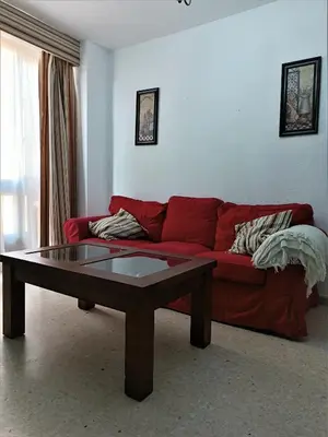 a living room with a red couch and a coffee table at Piso Calzada de la Infanta Tres Carabelas Sanlúcar de Barrameda in Sanlúcar de Barrameda