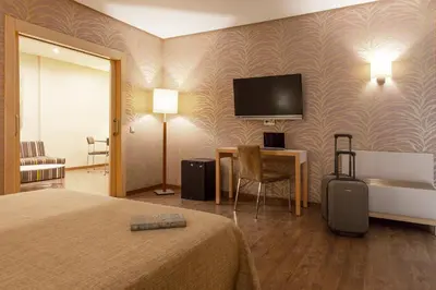 a hotel room with a bed and a television on a wall at Hotel Macià Doñana in Sanlúcar de Barrameda