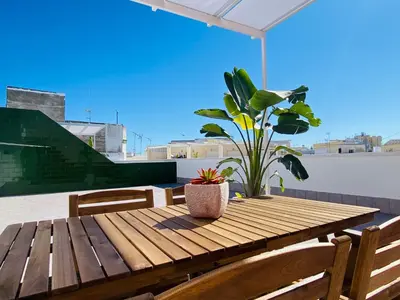 a wooden table with chairs and a potted plant on a roof at Summerlandrota Argüelles 4 in Rota