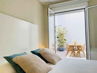 a bedroom with a bed and a balcony with a table at Summerlandrota Argüelles 4 in Rota