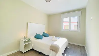 a bedroom with a white bed with blue pillows at Summerlandrota Argüelles 4 in Rota