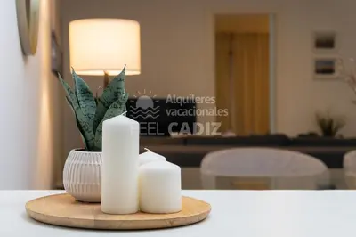 a table with two white candles and a vase at Apartamento El Mirador del Paso (Feel Cádiz) in Cádiz