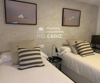 a hotel room with two beds and a tv on the wall at Apartamento El Mirador del Paso (Feel Cádiz) in Cádiz