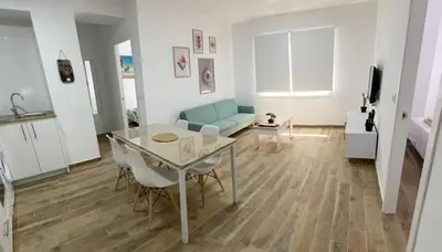 a living room with a table and a blue couch at Fantástico piso reformado zona centro San Miguel in Jerez de la Frontera