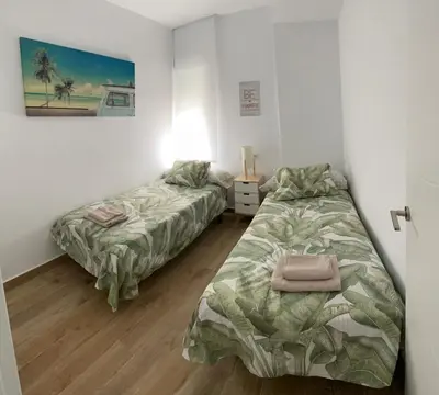 two beds in a room with white walls and wooden floors at Fantástico piso reformado zona centro San Miguel in Jerez de la Frontera