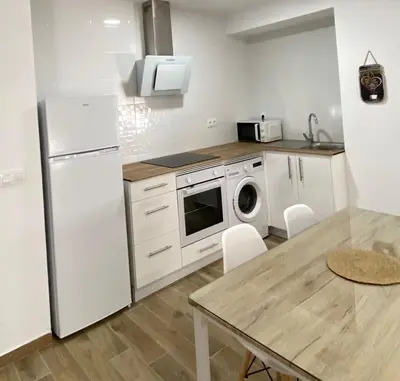 a kitchen with a white refrigerator and a table at Fantástico piso reformado zona centro San Miguel in Jerez de la Frontera