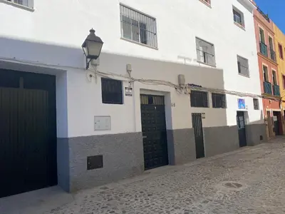 a white building with two garage doors and a street at Fantástico piso reformado zona centro San Miguel in Jerez de la Frontera