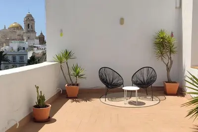 a balcony with two chairs and a table and plants at Ático en La Candelaria in Cádiz