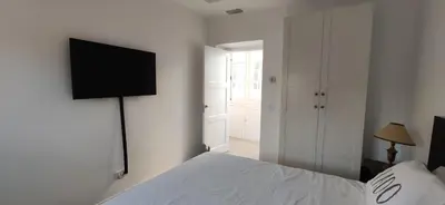 a bedroom with a white bed and a flat screen tv at Ático en La Candelaria in Cádiz