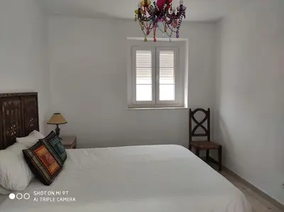 a bedroom with a white bed and a window at Ático en La Candelaria in Cádiz