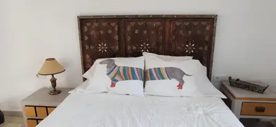 a bed with white sheets and pillows with a wooden headboard at Ático en La Candelaria in Cádiz