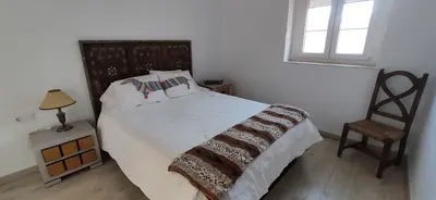 a bedroom with a bed with a chair and a window at Ático en La Candelaria in Cádiz