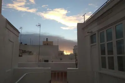 a view of a building with the sunset in the background at Ático en La Candelaria in Cádiz