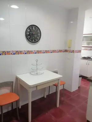 a white table with two chairs and a clock on the wall at Keka en Playa la Victoria con Ascensor Grupo AC Gestion in Cádiz