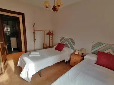 a bedroom with two beds and a chandelier at Keka en Playa la Victoria con Ascensor Grupo AC Gestion in Cádiz