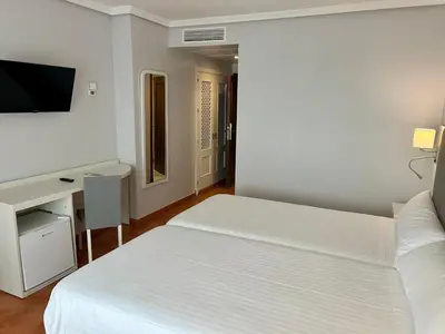 a white bedroom with a bed and a desk at Hotel Bahia Sur in San Fernando