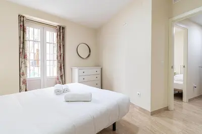 a white bedroom with a white bed and a window at Allo Apartments Consistorio Centro 2 Habitaciones in Jerez de la Frontera