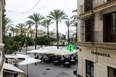 a group of tables and chairs in a street with palm trees at Allo Apartments Consistorio Centro 2 Habitaciones in Jerez de la Frontera