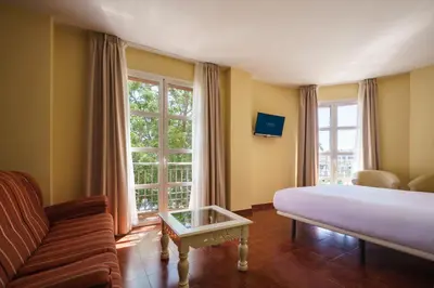 a bedroom with a bed and a couch and a table at Crisol Chiclana in Chiclana de la Frontera