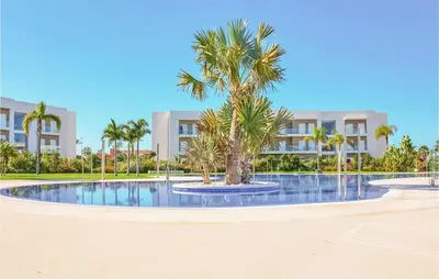 a palm tree in a pool in front of a building at Gorgeous Apartment In Chipiona in Chipiona