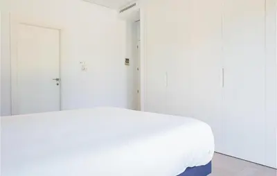 a white bed in a room with white walls at Gorgeous Apartment In Chipiona in Chipiona