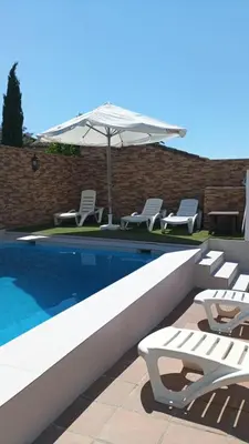 a swimming pool with lounge chairs and an umbrella at El Recuerdo in Arcos de la Frontera
